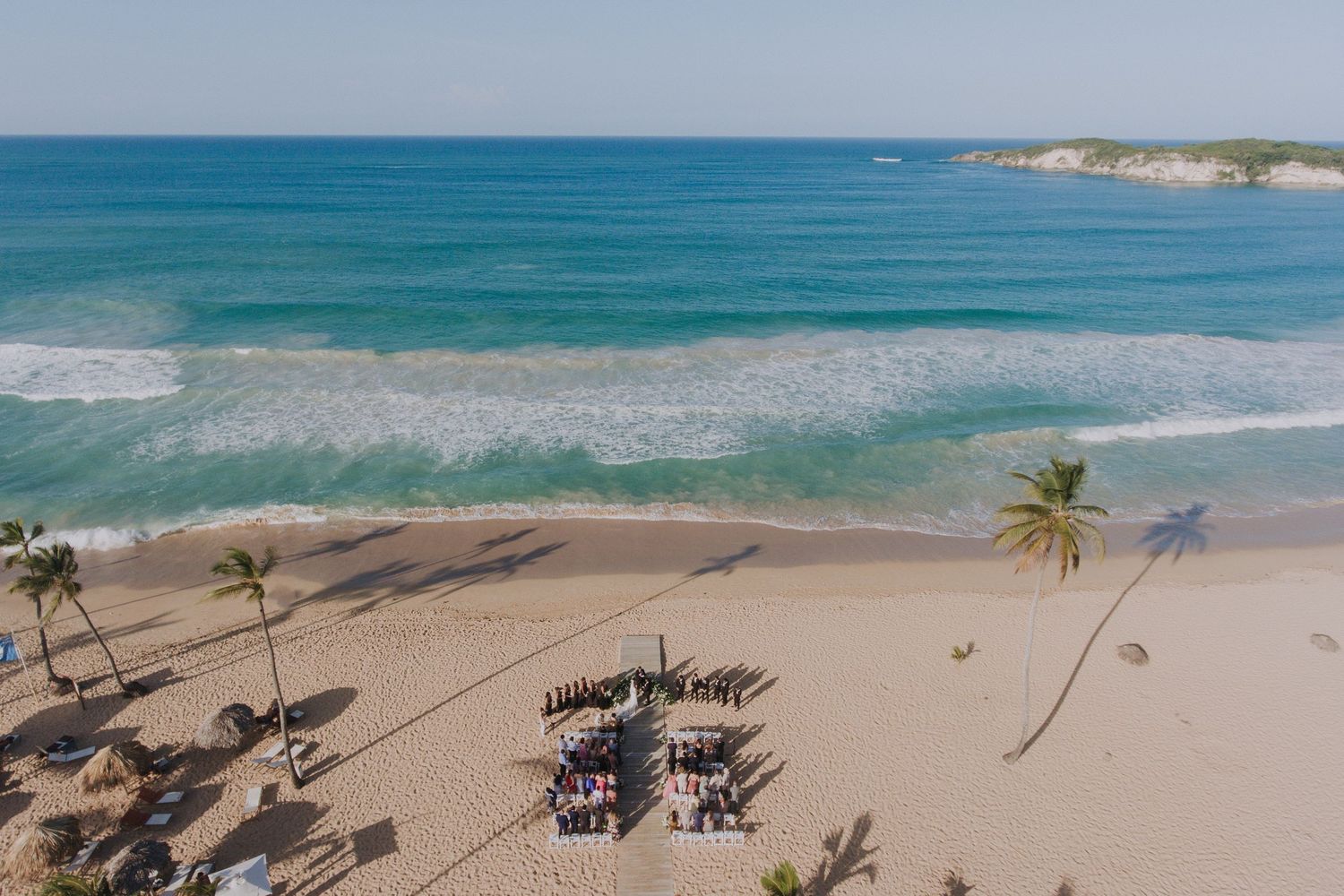 Aerial view of a pristine Caribbean beach with chairs and palm trees.