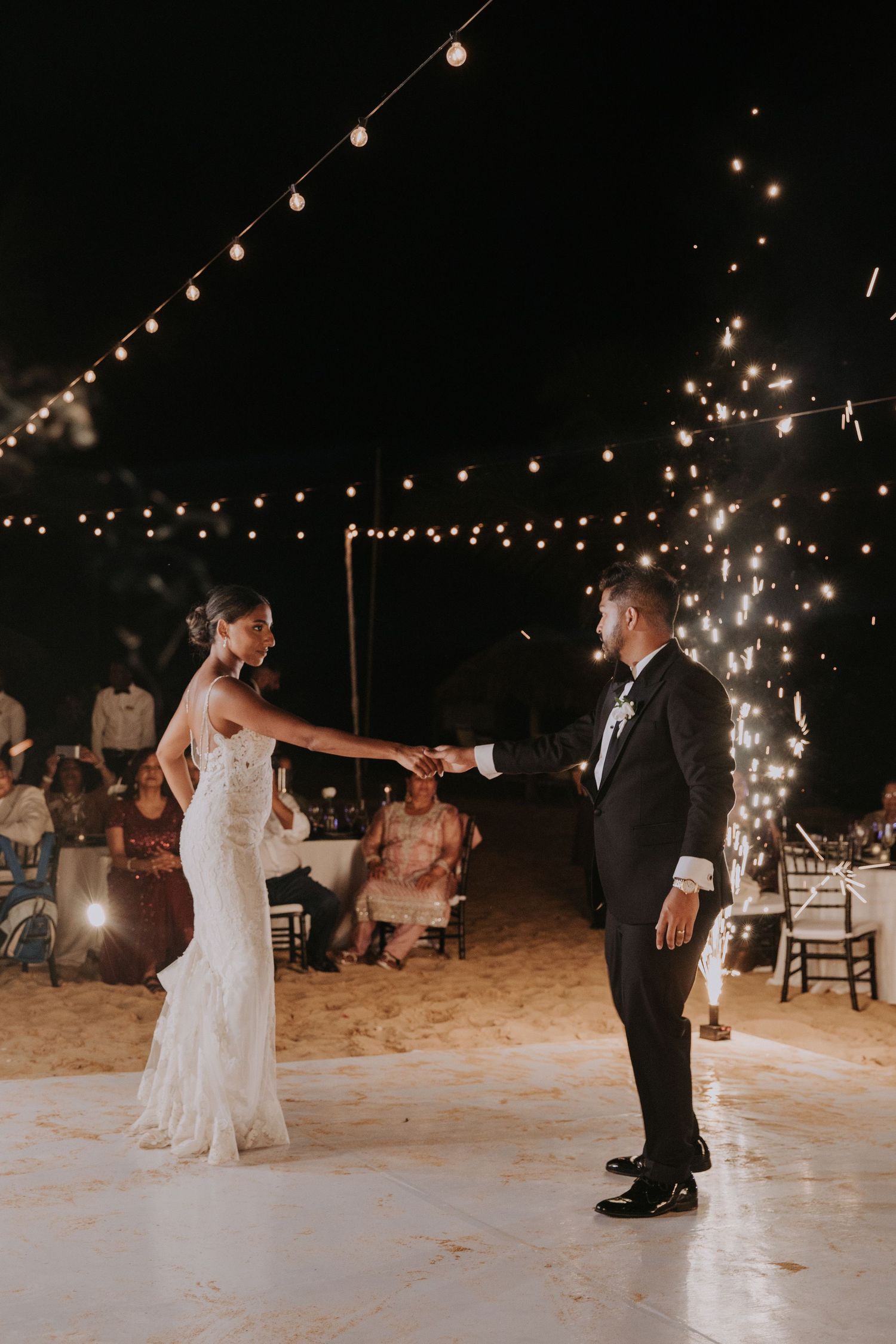 Newlyweds share their first dance on a decorated outdoor dance floor.