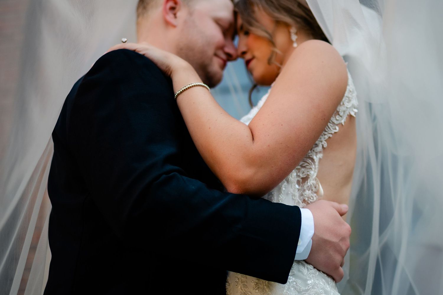 A bride and groom share romantic kisses in a collage of four wedding photos.