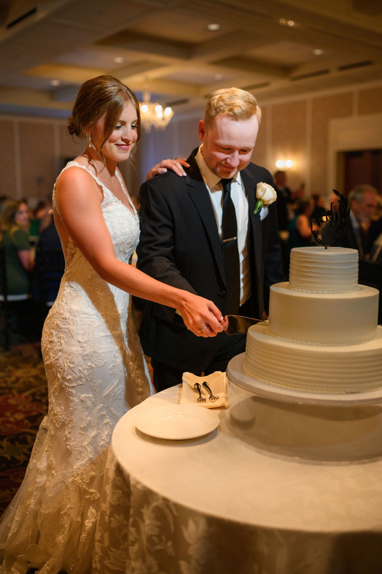 A couple performs their traditional wedding cake cutting ceremony at an elegant indoor reception.