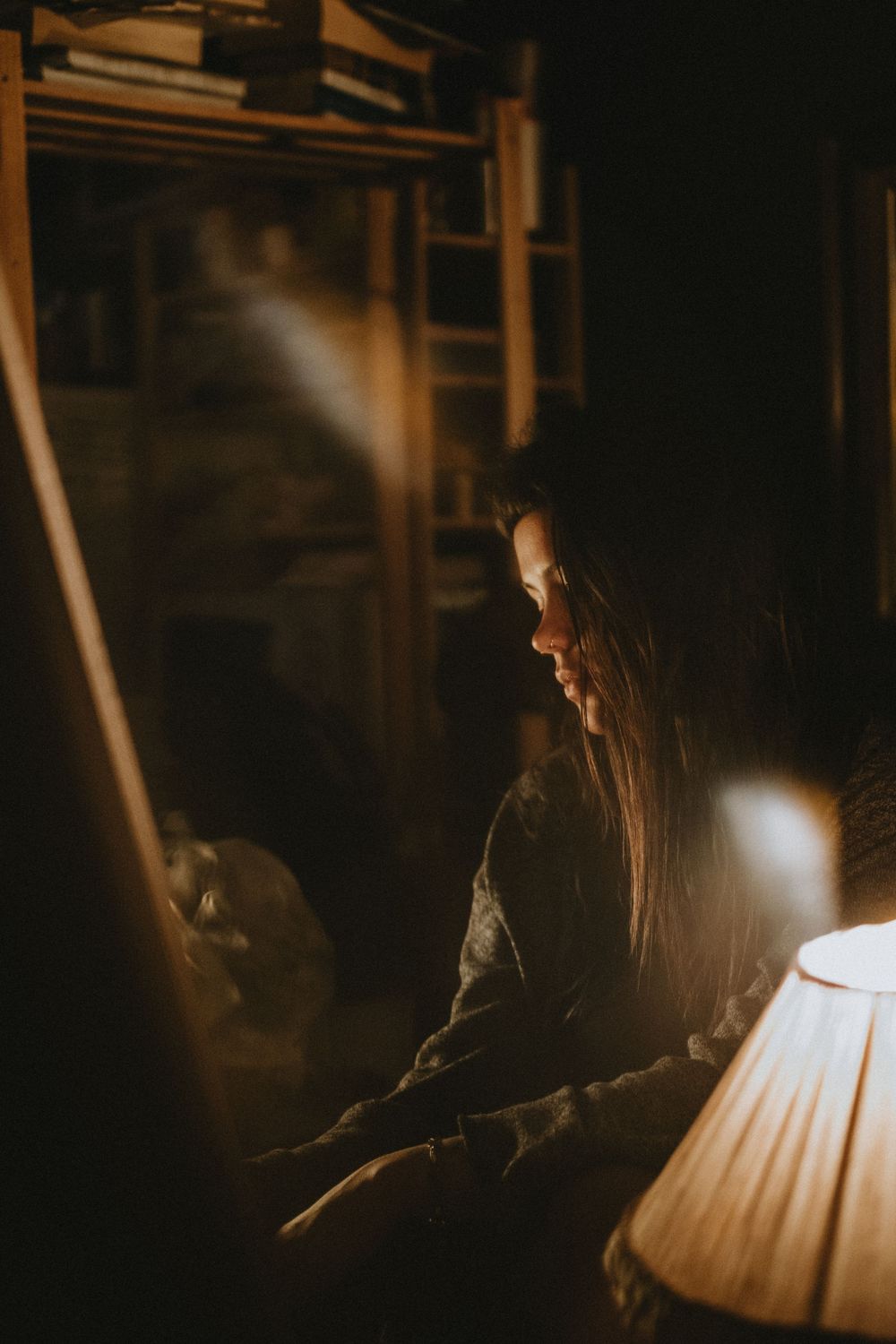 A moody portrait in warm lamplight showing someone in deep contemplation.