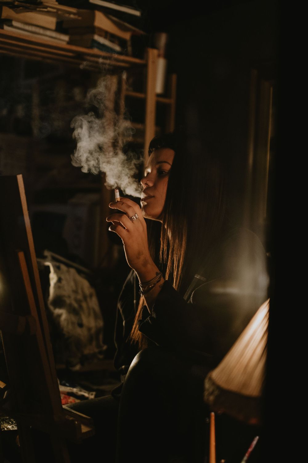 Smoke rises in a darkened room lit by a single light source.