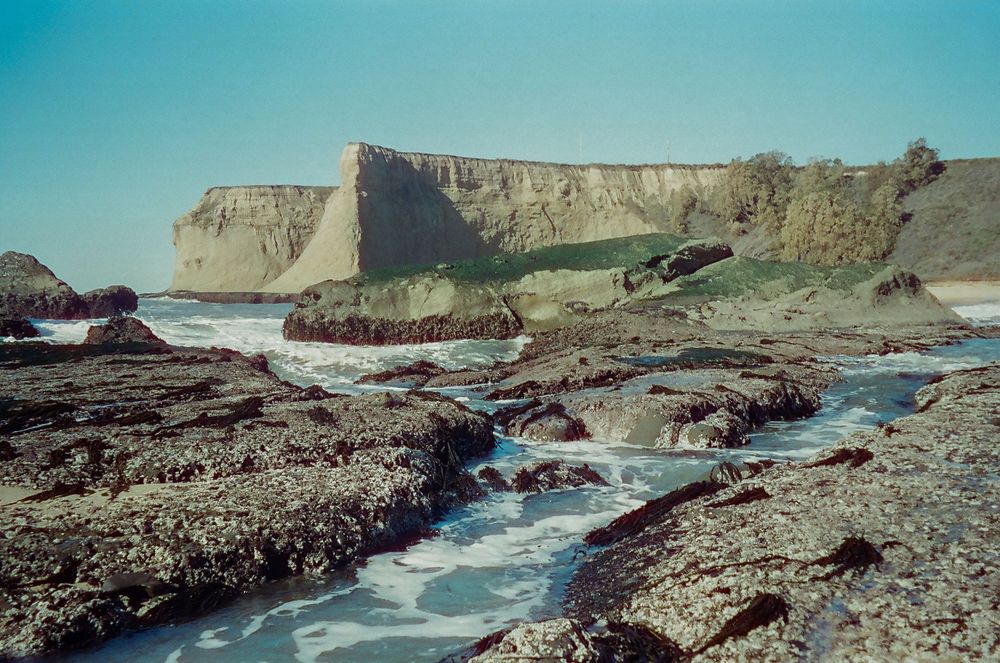 Rocky cove with white water rushing through narrow channels between coastal cliffs.