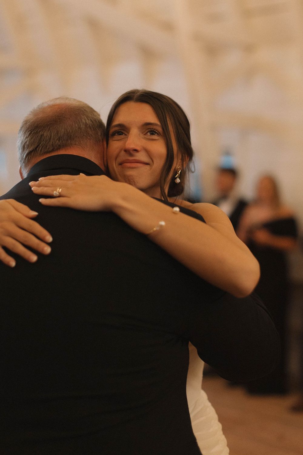 A close-up shot captures an emotional embrace during a wedding dance.