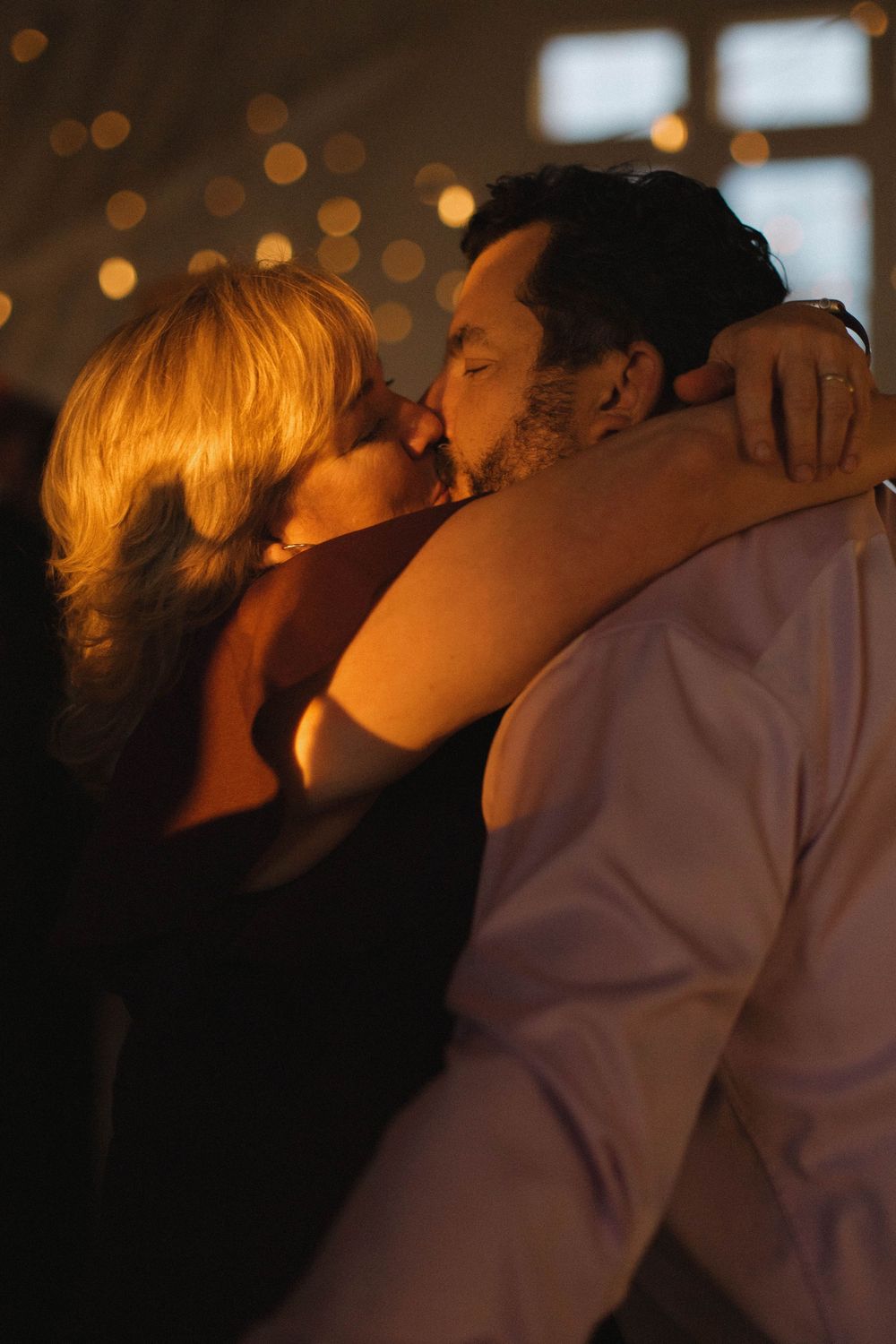 Silhouetted couples dance intimately under golden reception lighting.