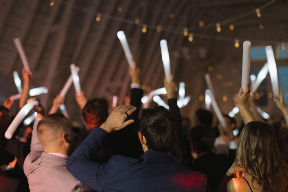 Wedding guests raise their arms in celebration during a reception dance party.