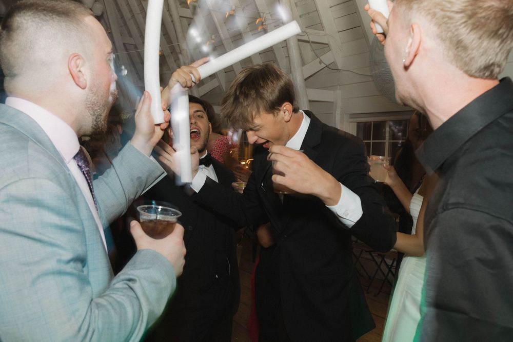 Wedding guests hold up glowing light sticks during an evening celebration.