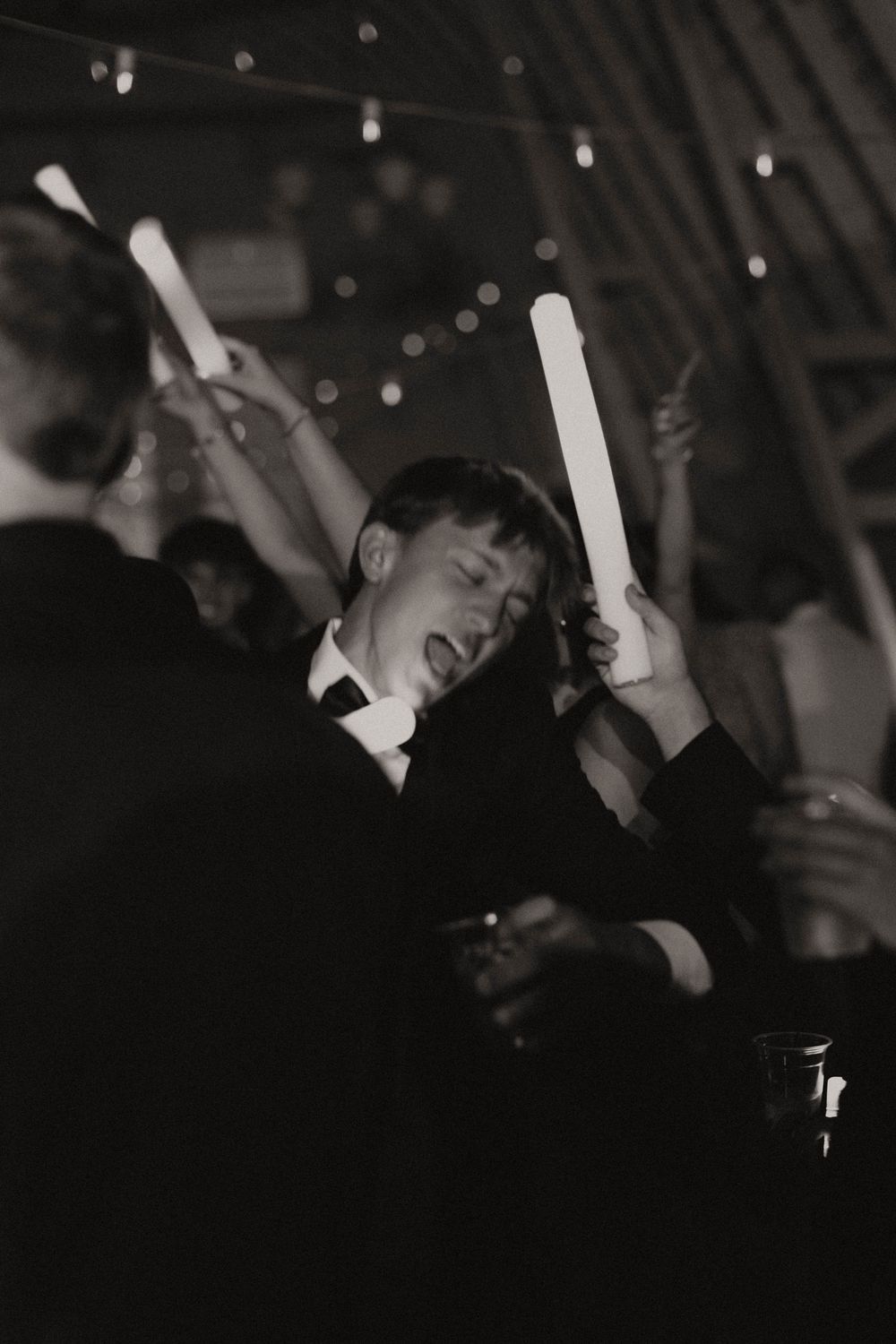 Dark silhouettes of wedding guests dancing beneath twinkling reception lights.