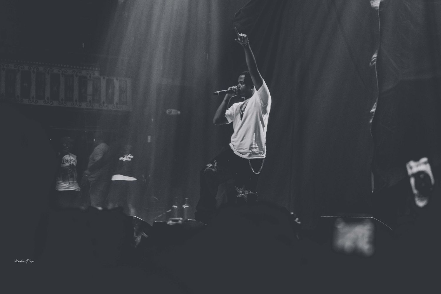 A series of black and white concert photos showing musicians performing on a dark stage with dramatic lighting.