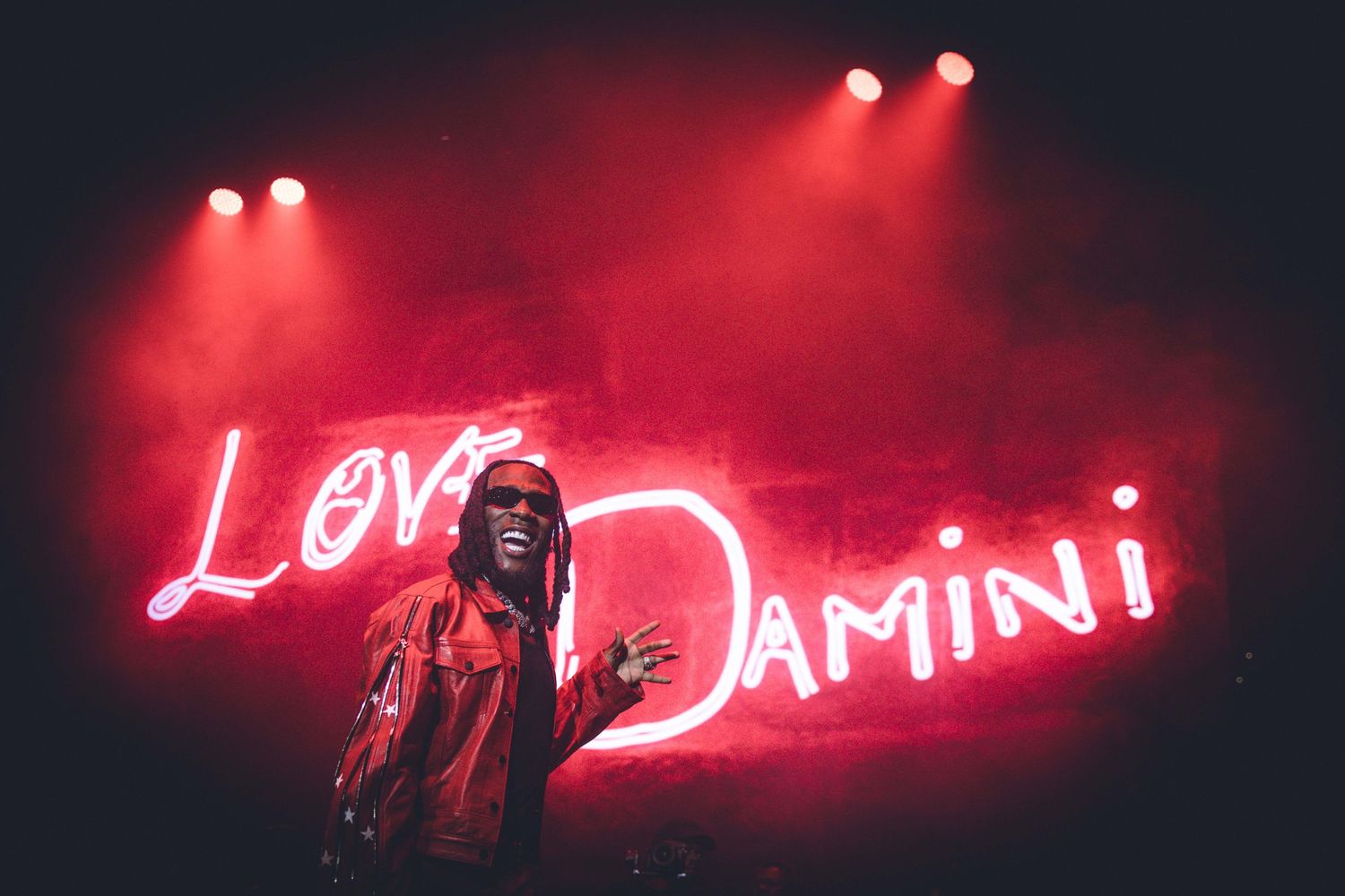 Neon red lights illuminate a dark stage during a dramatic concert performance.