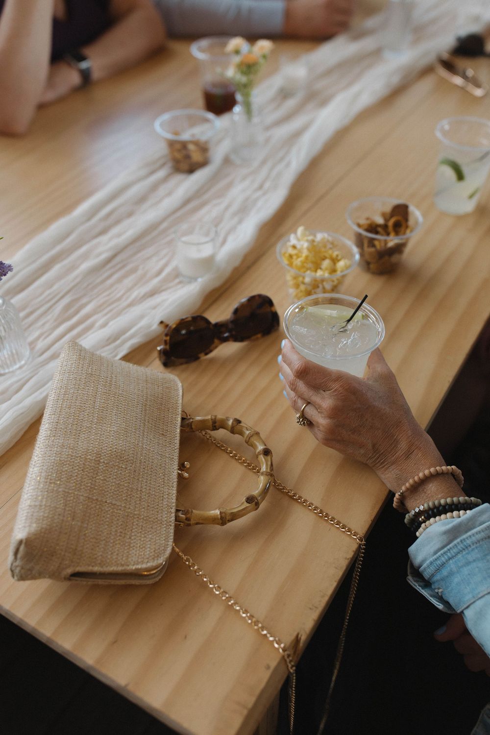 Close-up of hands arranging decorative elements on a textured tablecloth.