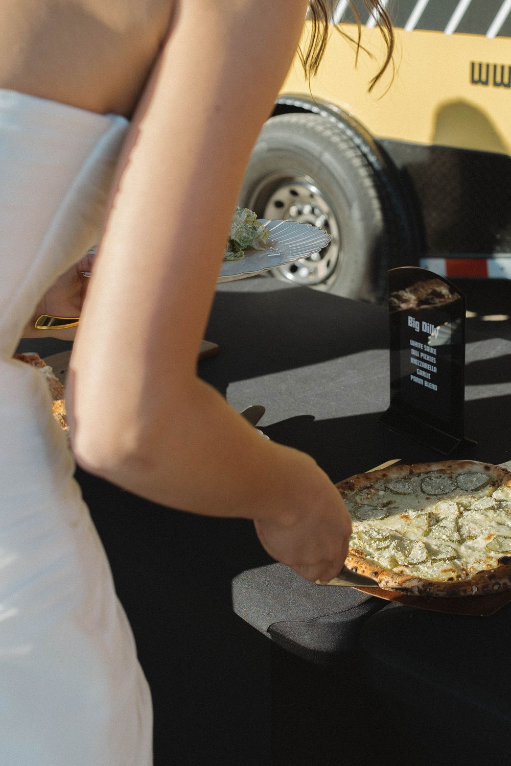 Close-up of hands preparing food on a black surface near food service equipment.