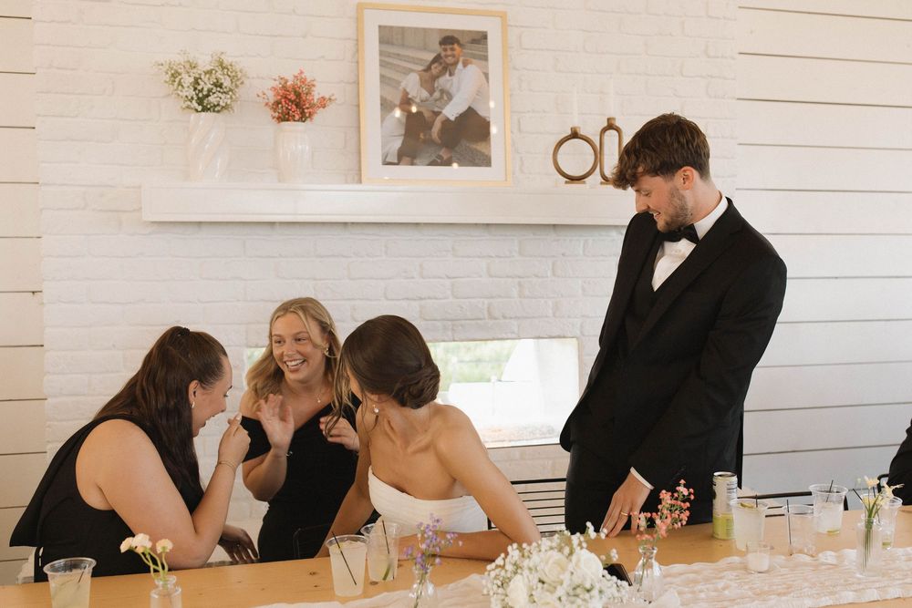 Wedding reception guests seated at tables in a bright white interior space.