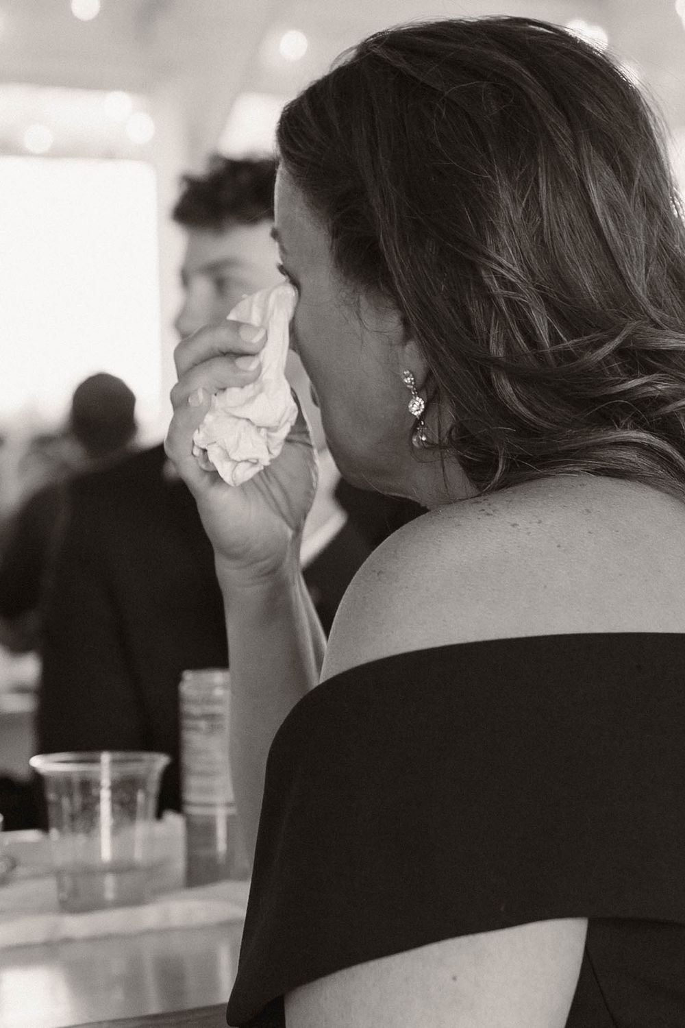 Wedding guest in black attire enjoys drinks at an elegant reception.