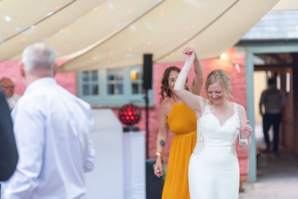 Wedding guests joyfully dancing and celebrating at an indoor reception.