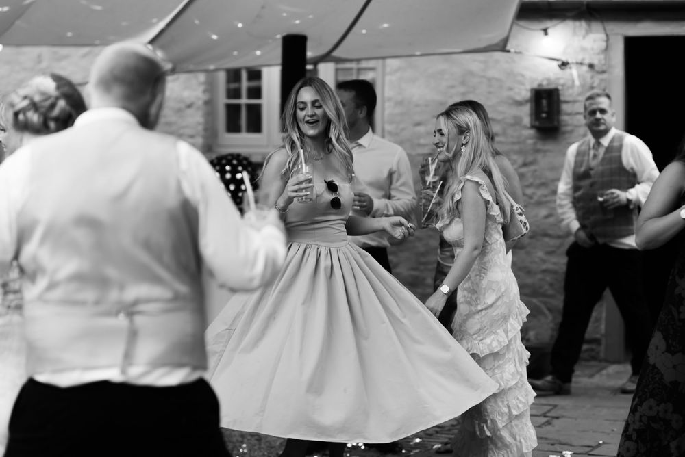 Wedding guests dancing together on a rustic wood floor at an indoor reception.