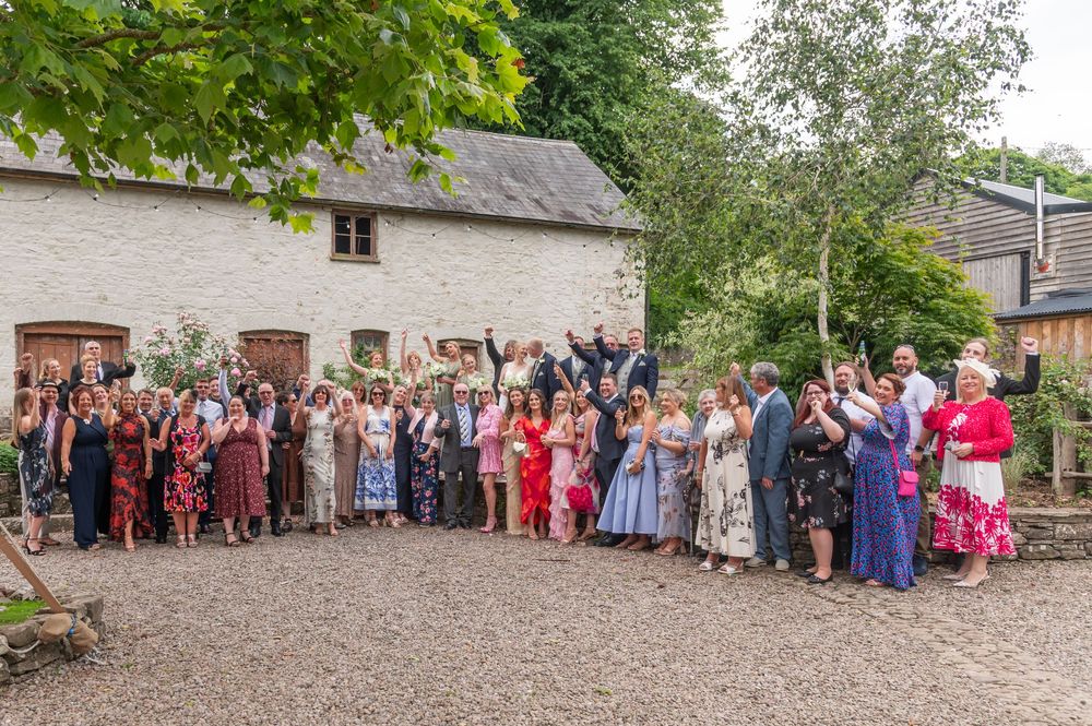 Wedding guests gathered outside a historic stone building for group photos.