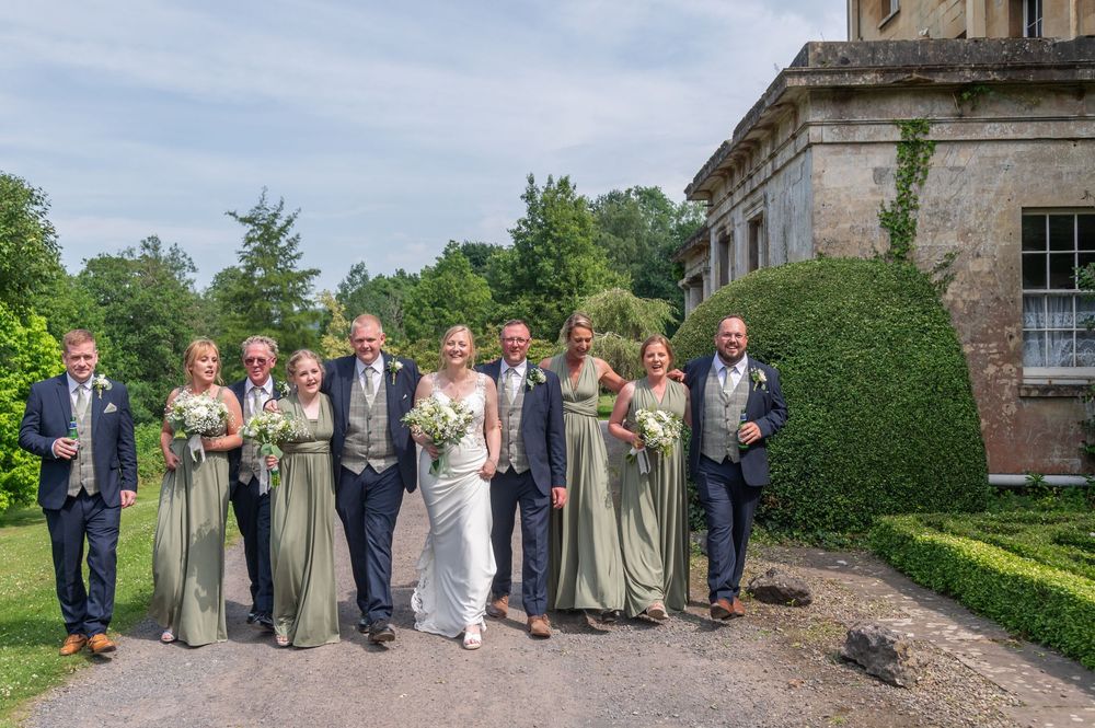 Wedding party in formal attire posing for photos in front of a historic building.