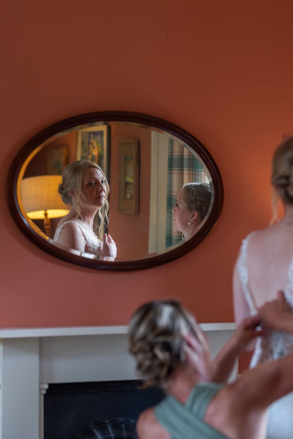 Vintage oval mirrors mounted on a coral-colored wall reflect preparation activities.