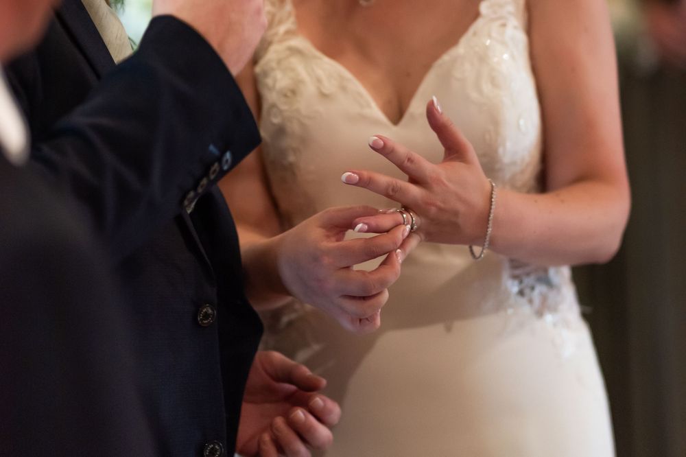 Close-up of wedding dress details and hands during ceremony.