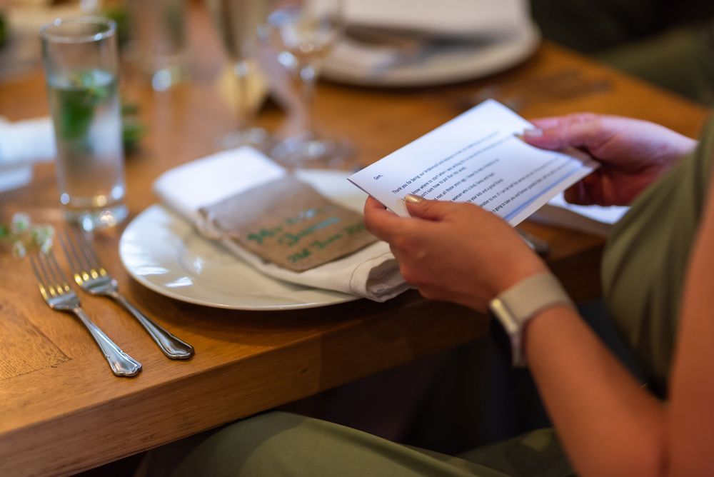 Close-up of place settings and menus on a wooden table at a wedding reception.