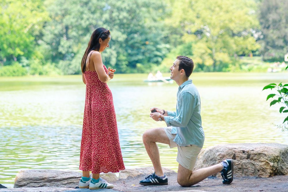 Lucas proposing to Emily at the San Remo lookout in Central Park with NYC skyline in the background.