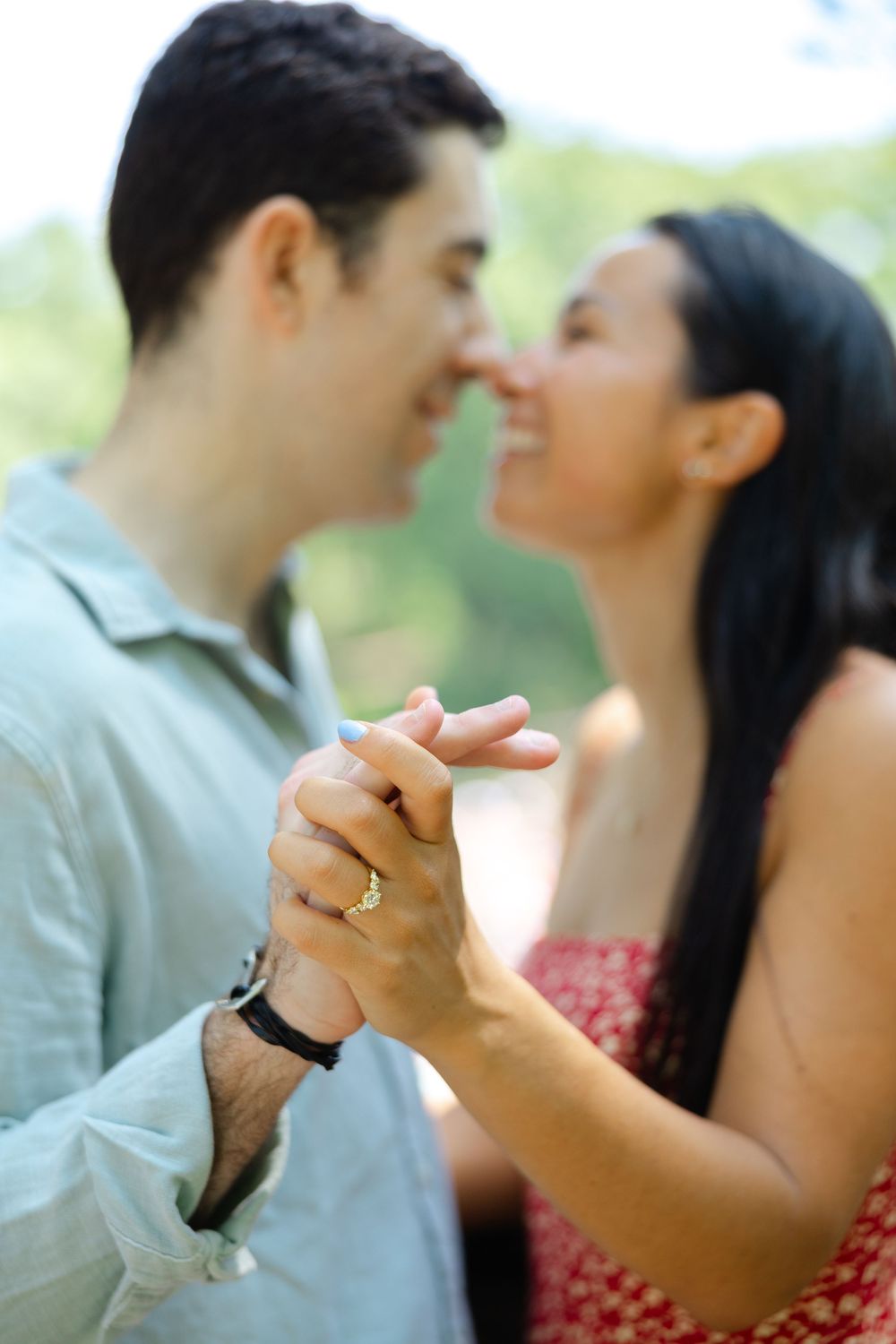 A romantic couple dancing together outdoors while holding hands with a soft blurred nature background.