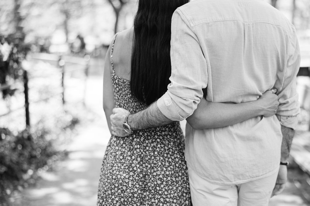 A romantic black and white photo showing a couple with their arms around each others' waists after a proposal in Central Park.