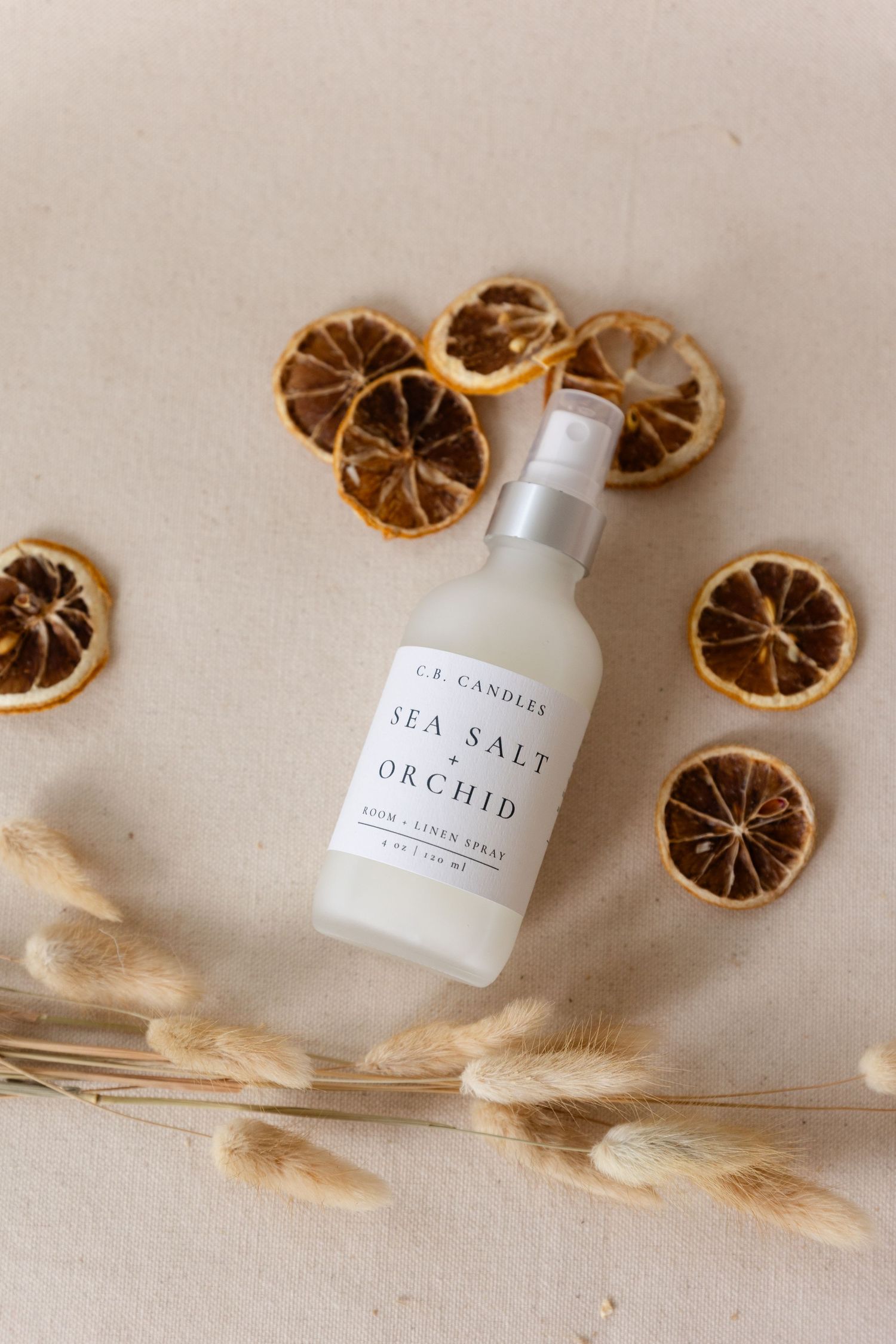flat lay of room spray with dried oranges around it