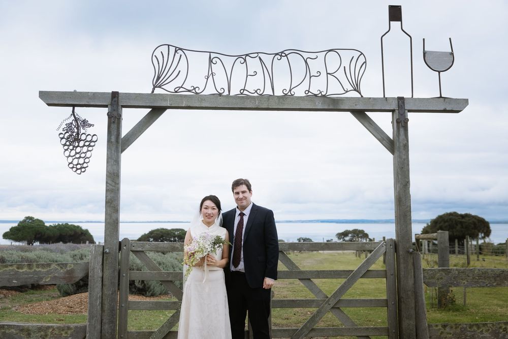 Wedding ceremony setup with rustic wooden arbor and wine-themed decorations in countryside setting.