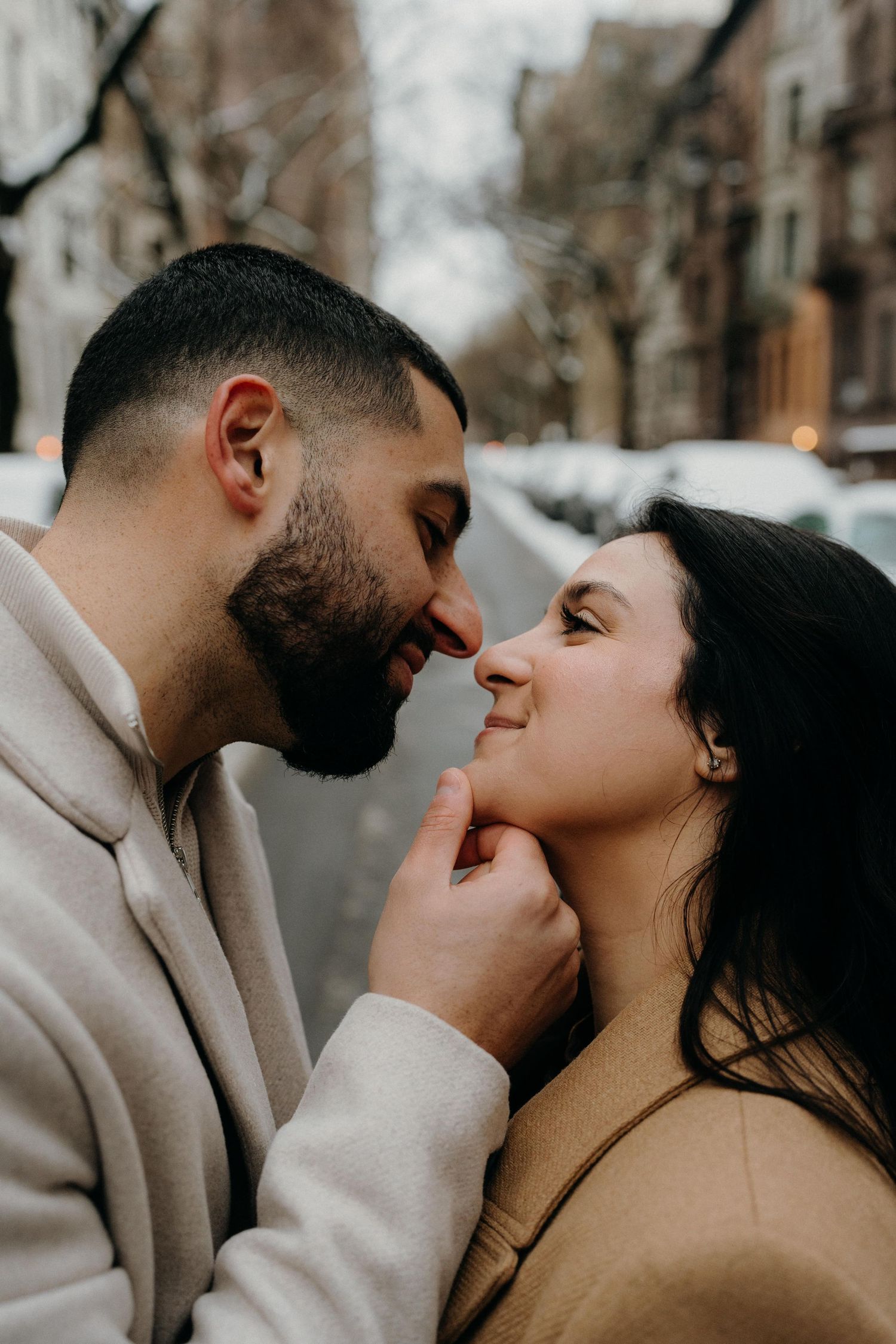Intimate close-up of couple sharing tender moment on winter city street.