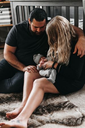 Sweet family moment with newborn baby in grey outfit on plush rug.  Indoor Newborn Session Arlington Texas