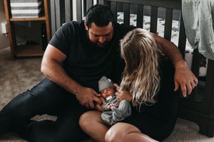 Intimate family moment with sleeping baby in grey clothing.  Indoor Newborn Session Arlington Texas