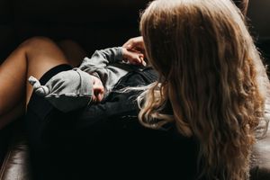 Peaceful moment with sleeping baby in grey outfit on dark furniture.  Indoor Newborn Session Arlington Texas