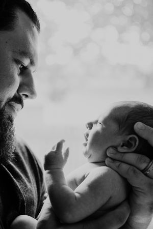 An intimate black and white portrait of a tender moment between parent and newborn.  Indoor Lifestyle Session Denton Texas