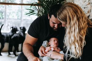 A heartwarming family moment with a laughing baby in a bright living room with decorative elements.  Indoor Lifestyle Session Denton Texas