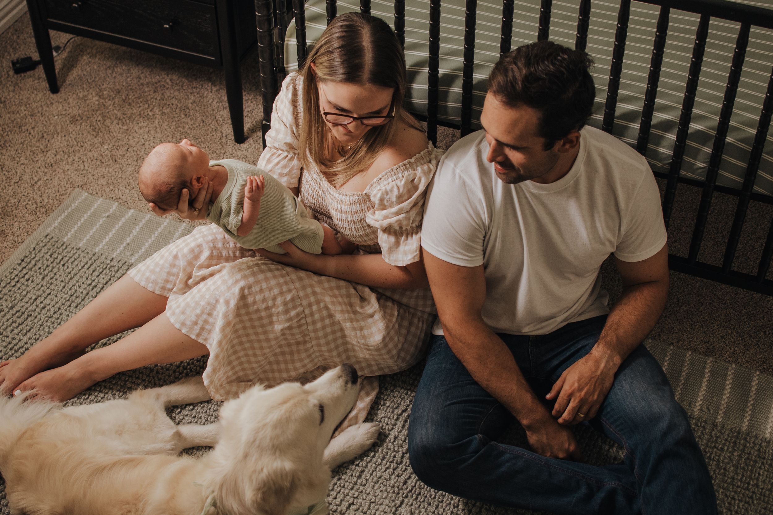 A family relaxes on carpet with their white dog while spending time with their newborn. Indoor Newborn Session Saginaw Fort Worth Texas