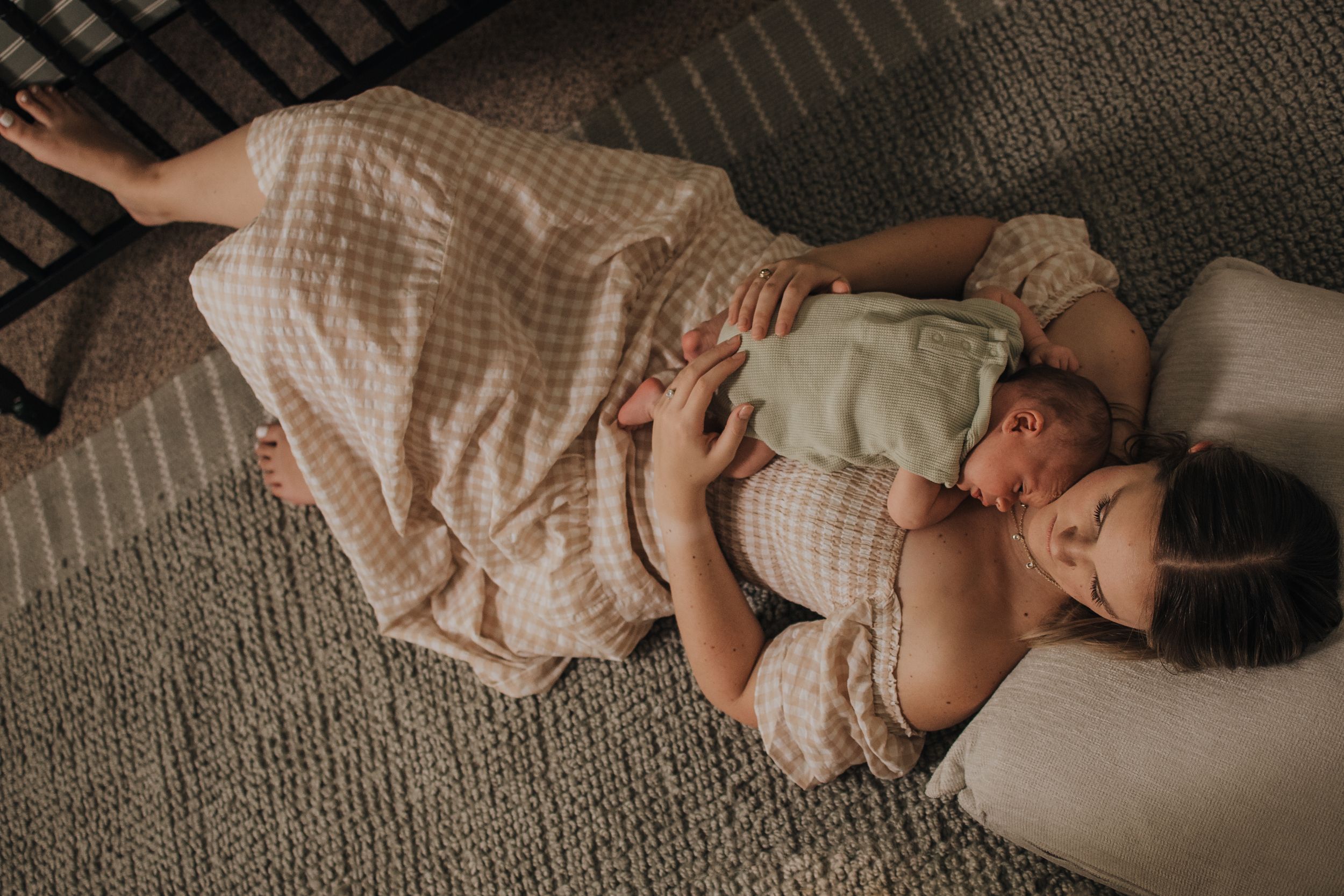 An intimate lifestyle photo of parent and newborn resting together on plush carpet.  Indoor Newborn Session Arlington Texas