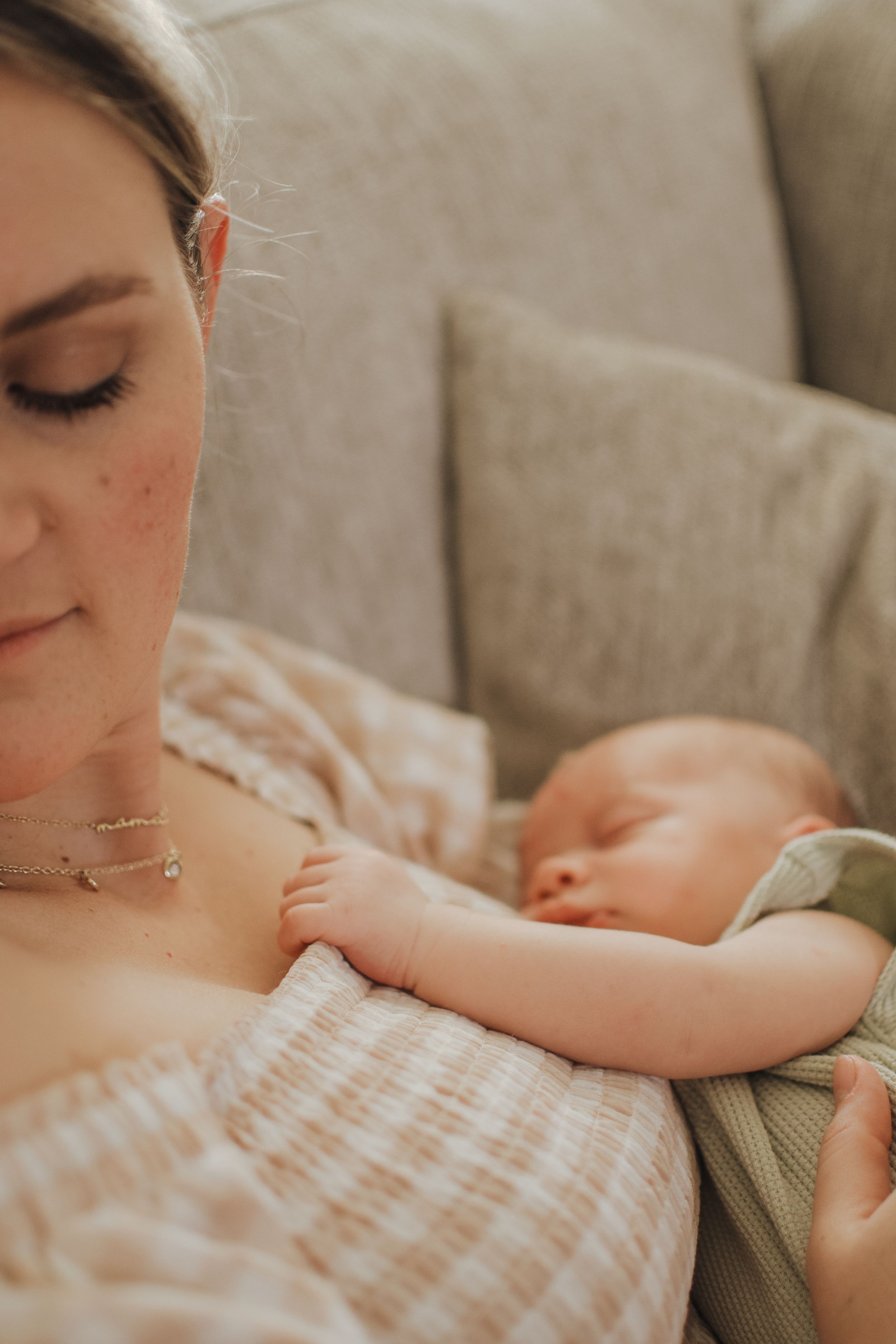 Close-up of a sleeping baby nestled against parent wearing striped fabric.  Indoor Newborn Session Arlington Texas