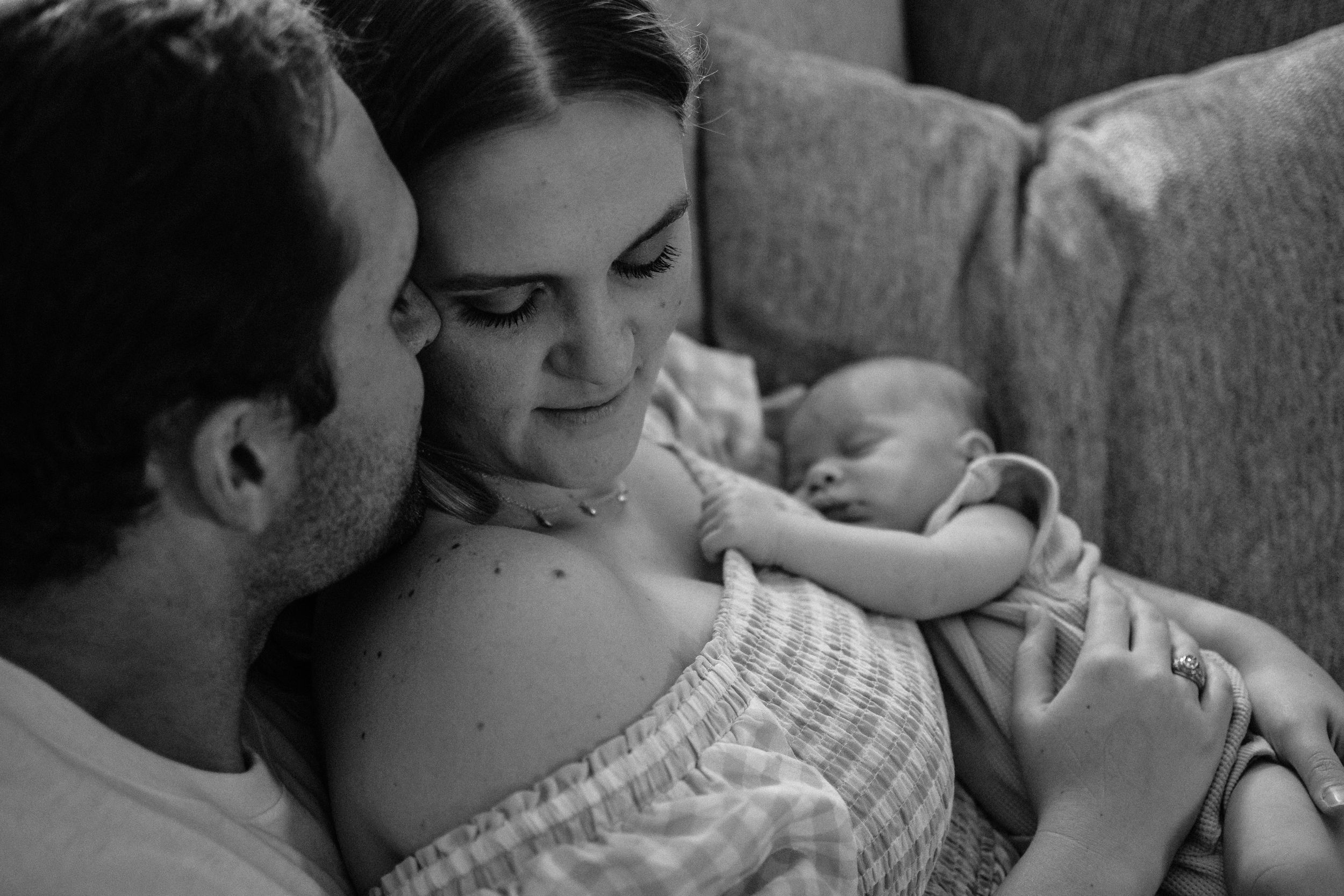 A tender black and white family moment with a sleeping newborn on a couch.  Indoor Newborn Session Saginaw Fort Worth Texas