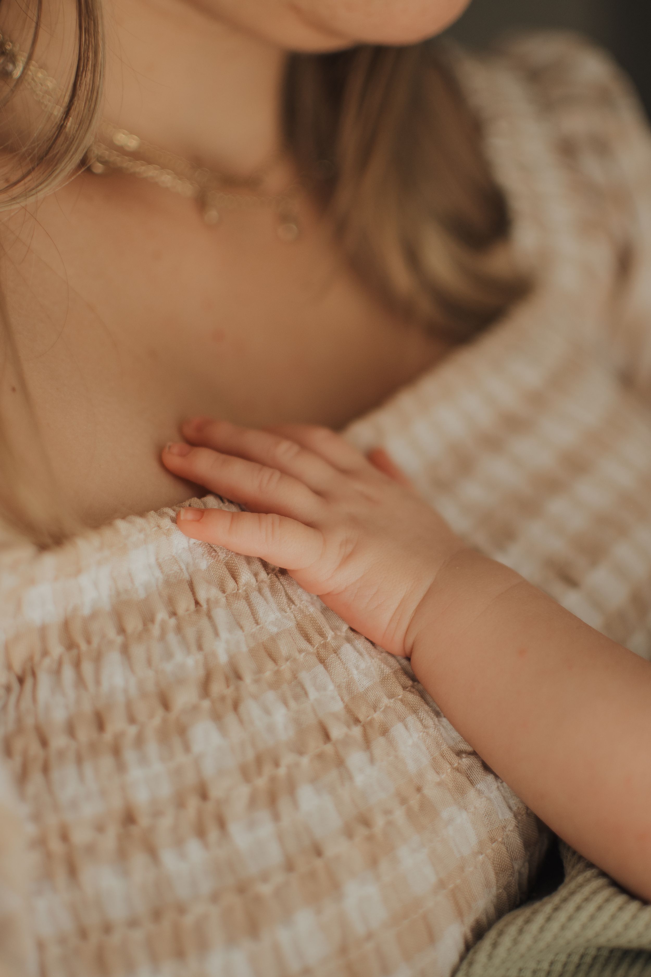 Tiny baby hand resting on striped fabric in warm tones.  Indoor Newborn Session Arlington Texas