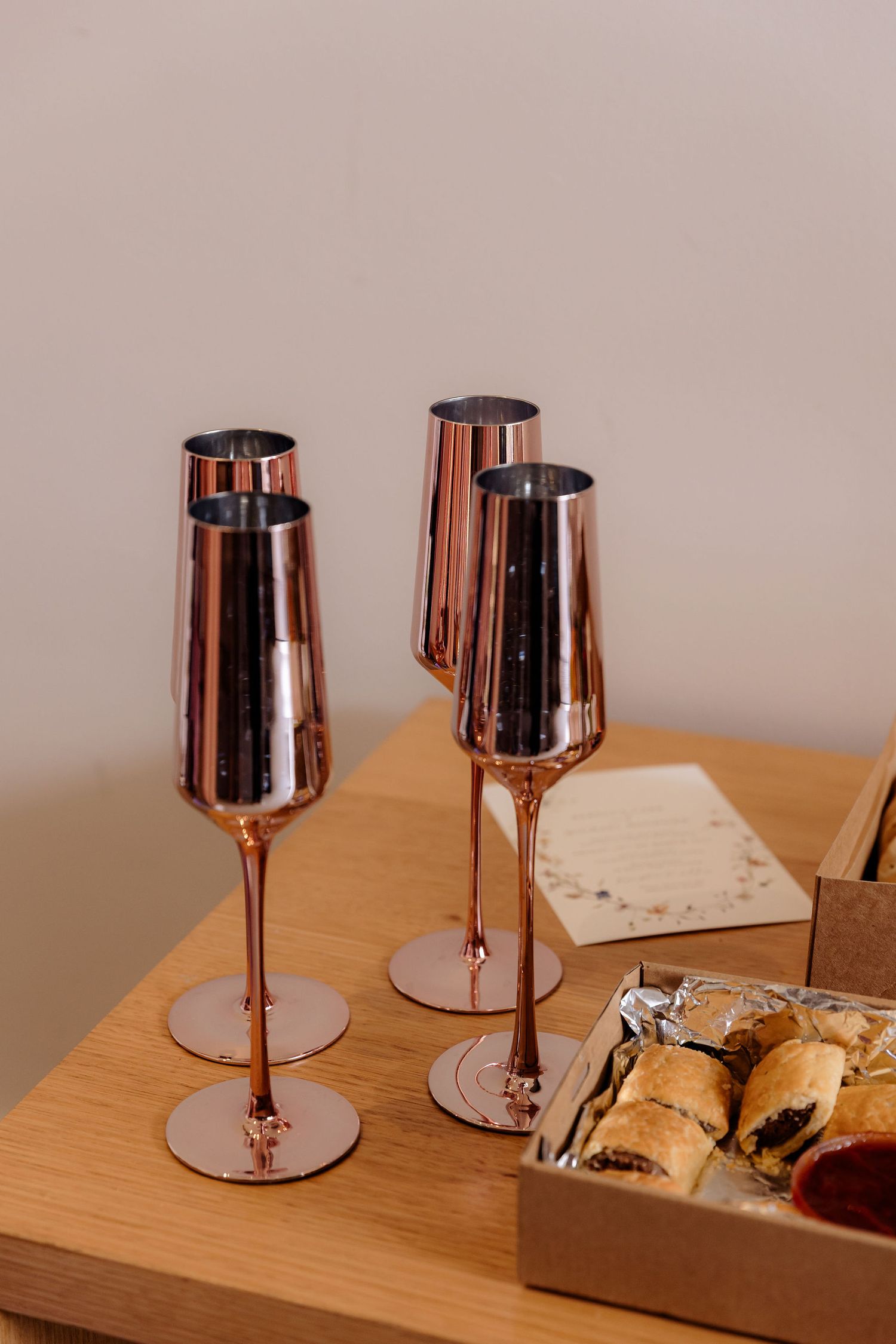 Rose gold wine glasses arranged on wooden table with decorative elements.
