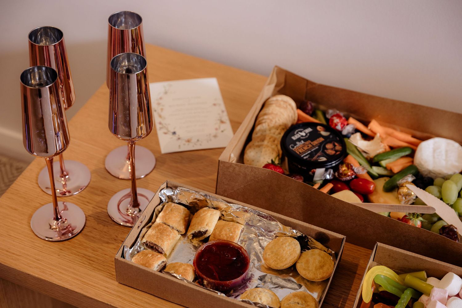 A series of wine glasses and appetizer plates lined up on a wooden table during a wine tasting event.