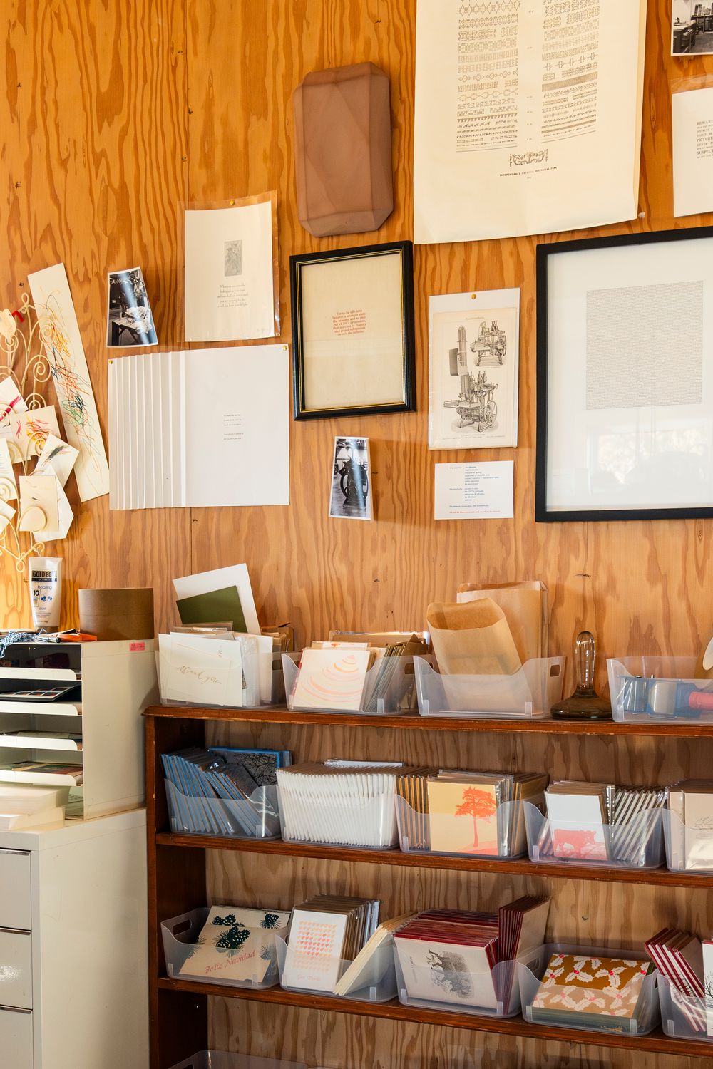 Vintage printing shop wall with framed artwork and organized paper storage shelves.