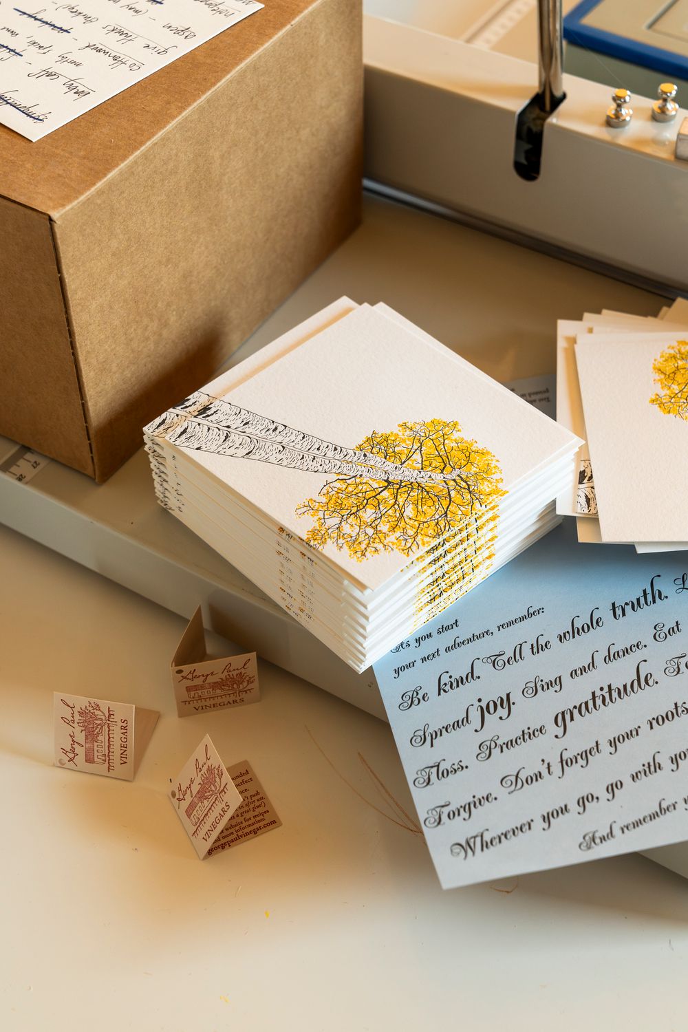 Stack of letterpress cards with yellow floral designs and calligraphy text.