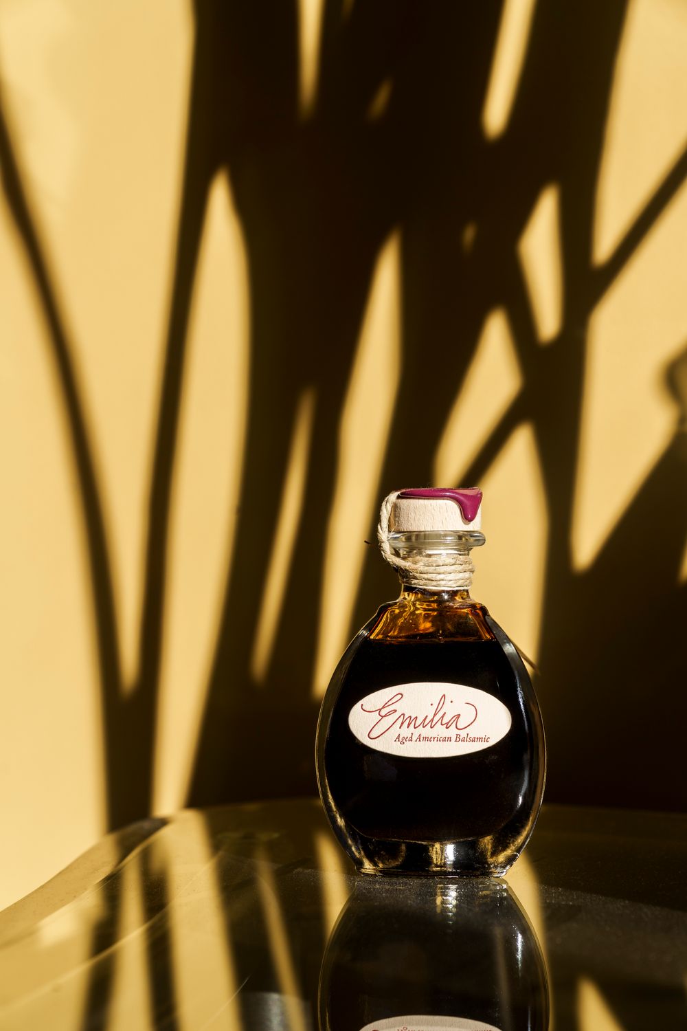 Glass bottles of artisanal vinegar casting dramatic shadows against a warm background.