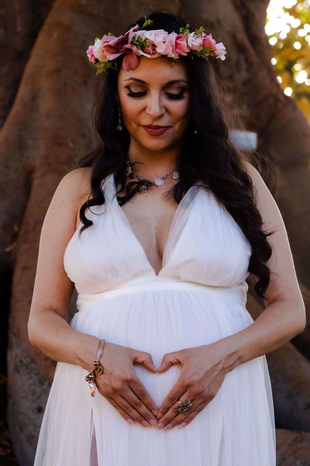 An ethereal maternity portrait in white dress and floral crown against tree roots, Fremont, CA