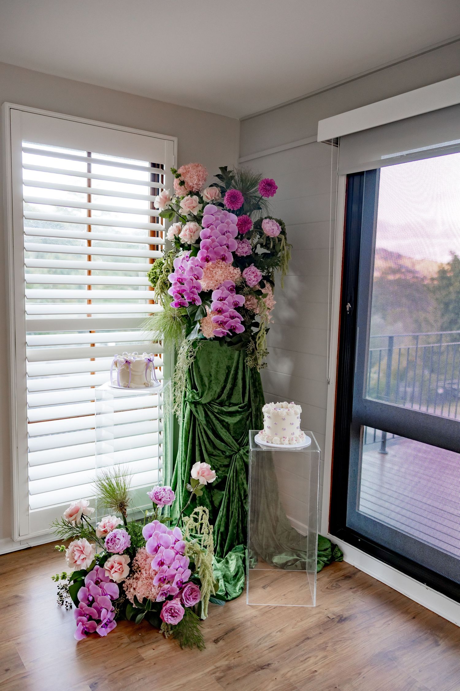 Elegant floral arrangement with pink and white flowers cascading from a tall green display stand by a window.