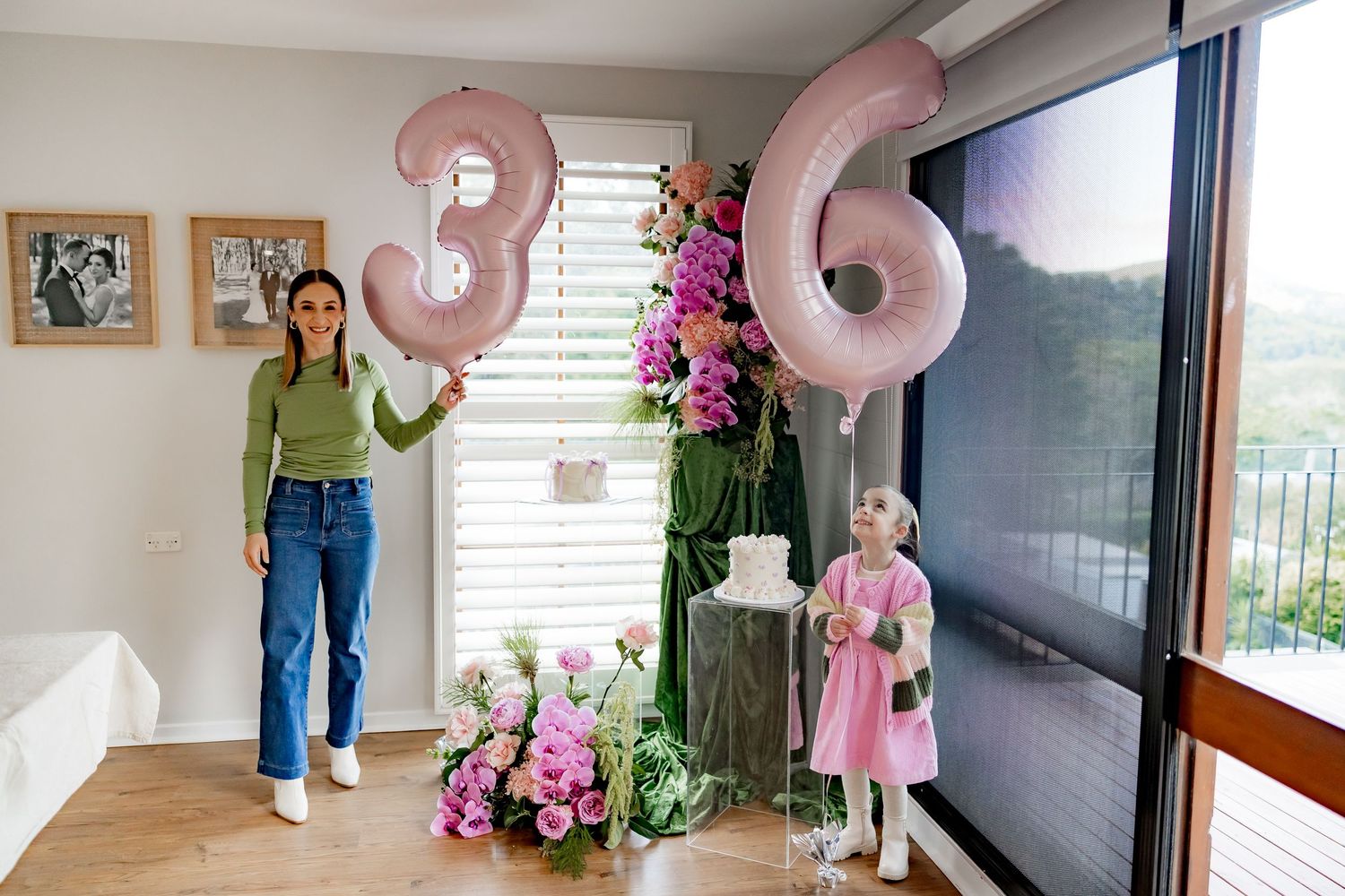 Pink balloon numbers display 36 with decorative flowers and greenery in a modern living room setting.