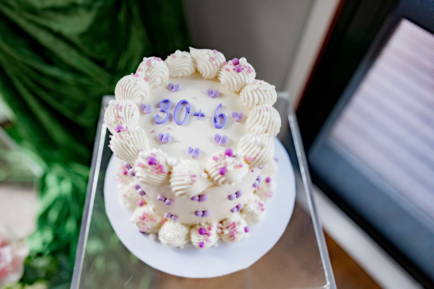 White frosted cupcakes arranged in a semi-circle on a plate with purple and pink sugar decorations.